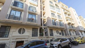 Un edificio residencial de varios pisos con balcones, una zona de estacionamiento y un letrero que indica prohibido estacionar.