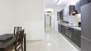 Una cocina moderna con armarios oscuros, electrodomésticos de acero inoxidable y un comedor con una mesa y sillas de madera.