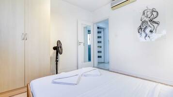 A bedroom with a bed, a wardrobe, a door leading to a staircase, and a wall-mounted air conditioner.