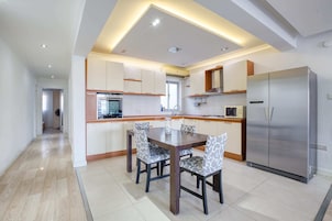 Una cocina moderna con comedor, que cuenta con una isla central, electrodomésticos de acero inoxidable y sillas estampadas.
