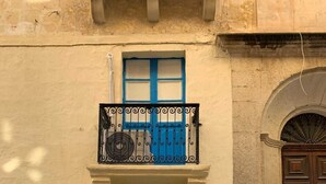 A building with a blue door, a balcony with a metal railing, and a brown door to the right. - Valletta Studio (Valletta)