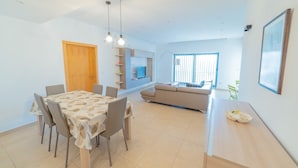 A modern living room with a dining table, sofa, and a TV. - Luxury Seaview & Pool (Mellieha)