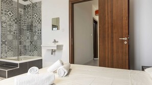 Una habitación de hotel con una cama, un baño con ducha, un lavamanos y un espejo.