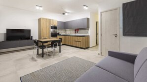 A modern kitchen with a dining area, a flat-screen TV, and a gray sofa. - Gzira Suite 13 (Gzira)