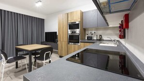 A modern kitchen with a wooden cabinet, a built-in oven, and a sink. - Gzira Suite 13 (Gzira)