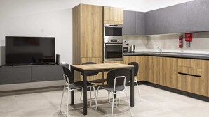 A modern kitchen with built-in appliances, a dining area with a table and chairs, and a flat-screen TV. - Gzira Suite 13 (Gzira)