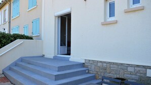 A building with a set of concrete steps leading to a door, a bench, and a small table. - L'estran - Maison sur la Digue Avec vue mer (Courseulles-sur-Mer)