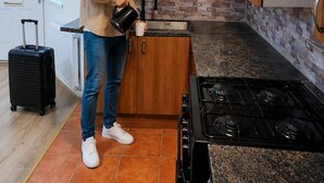 A modern kitchen with a gas stove, wooden cabinets, and a tiled backsplash.