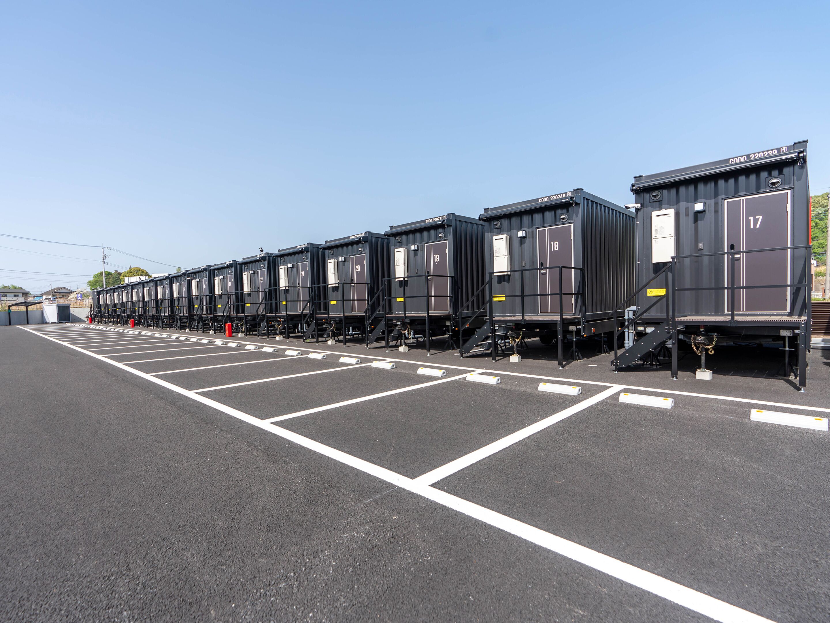 Een rij zwarte treinwagons geparkeerd op een parkeerplaats met witte lijnen die de parkeerplaats afbakenen.