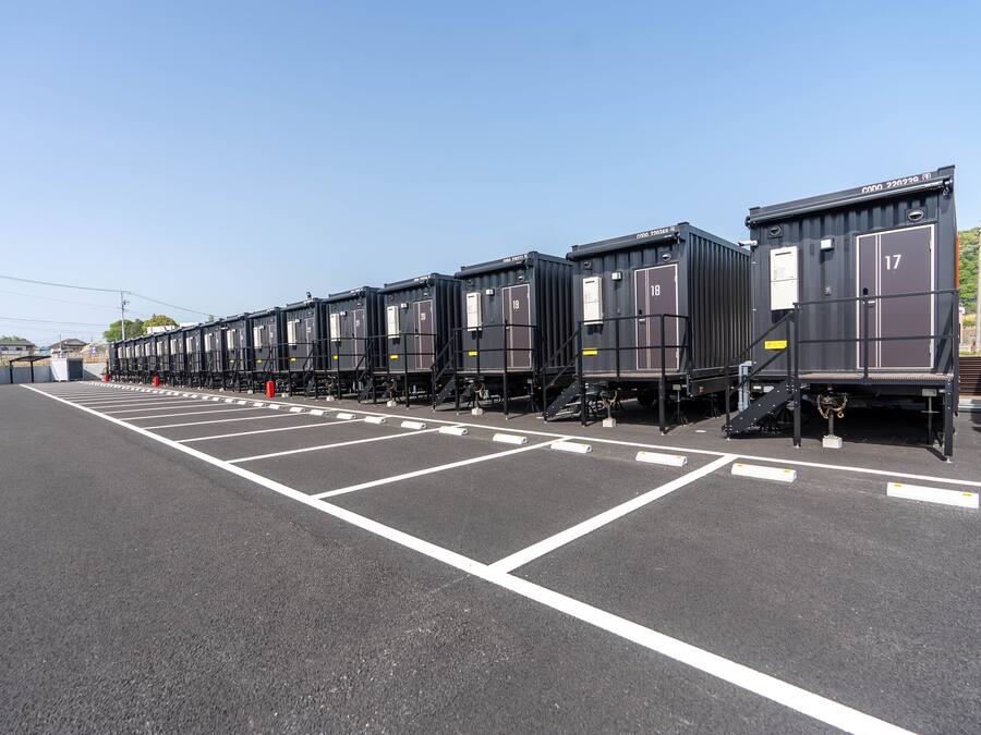 A row of black train carriages parked in a parking lot with white lines marking the spaces.