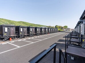 A row of portable cabins with steps leading to the entrance, arranged in a parking lot with clear markings. - HOTEL R9 The Yard Midori (Midori)