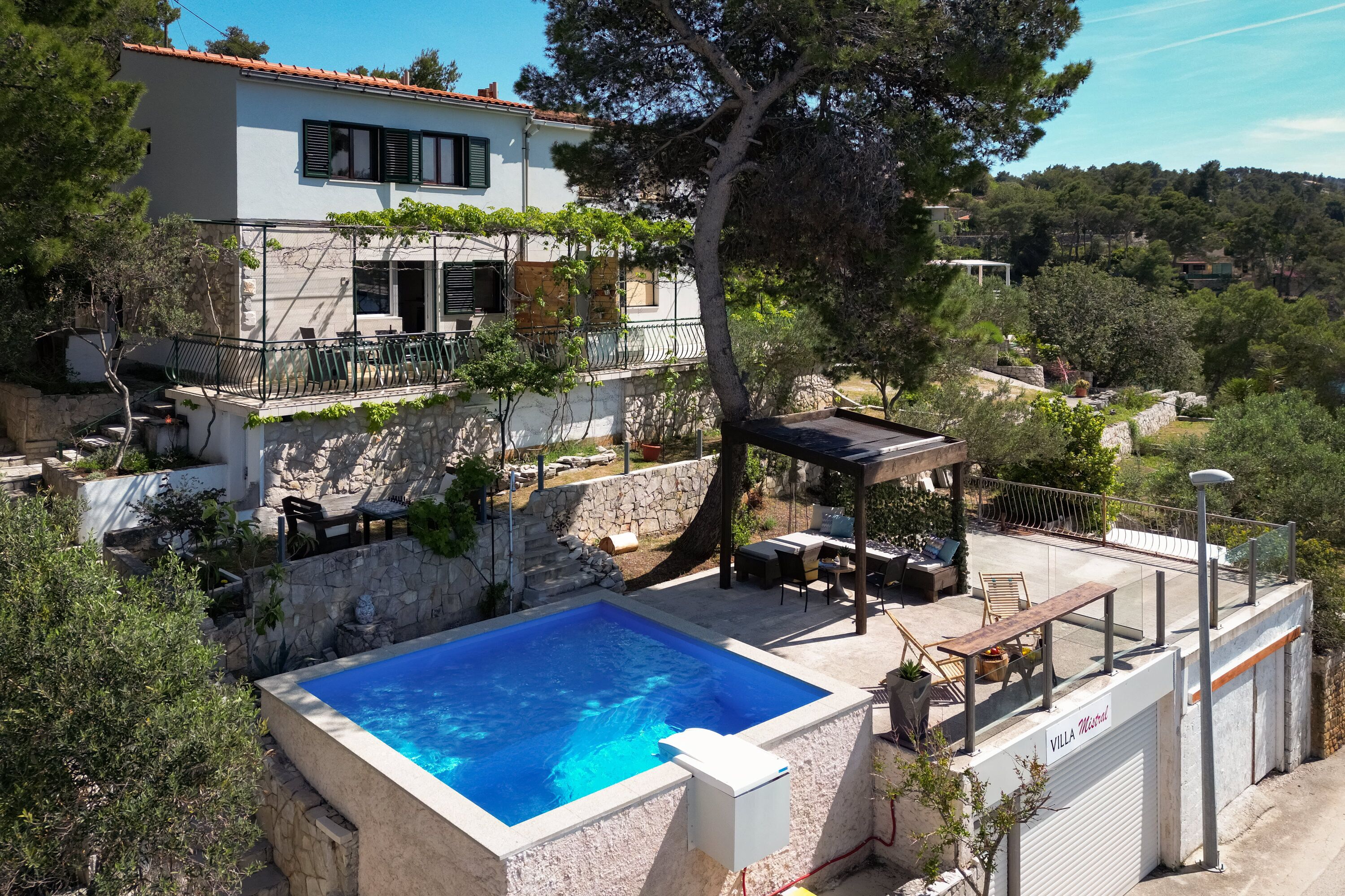 Une villa dotée d’une piscine, d’un espace salon extérieur et d’un mur en pierre.
