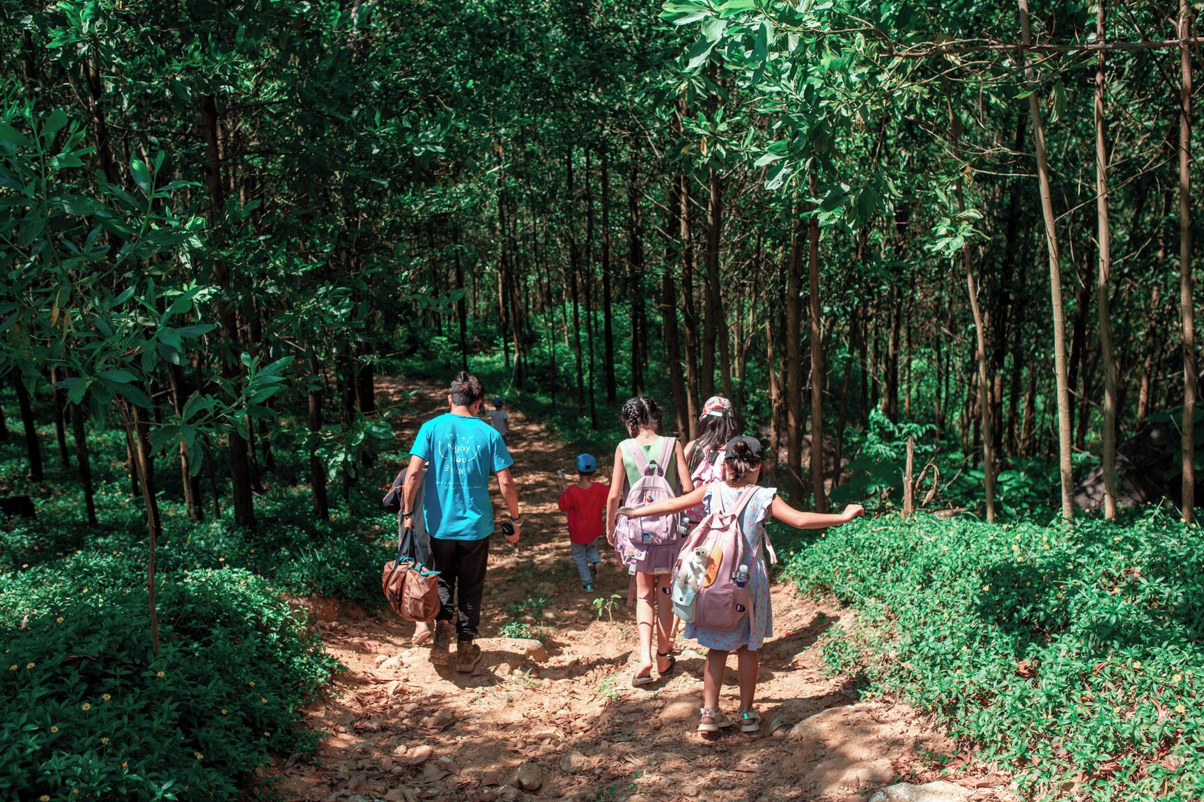 A group of people walking on a dirt path in a forested area.
