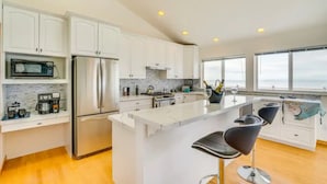 A modern kitchen with white cabinets, stainless steel appliances, and a large island with bar stools.