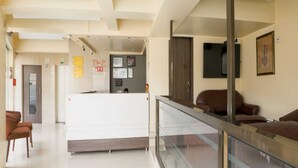 Eine großzügige Lobby mit Empfangstresen, einer Sitzecke und einem Glasgeländer mit Blick ins Innere.