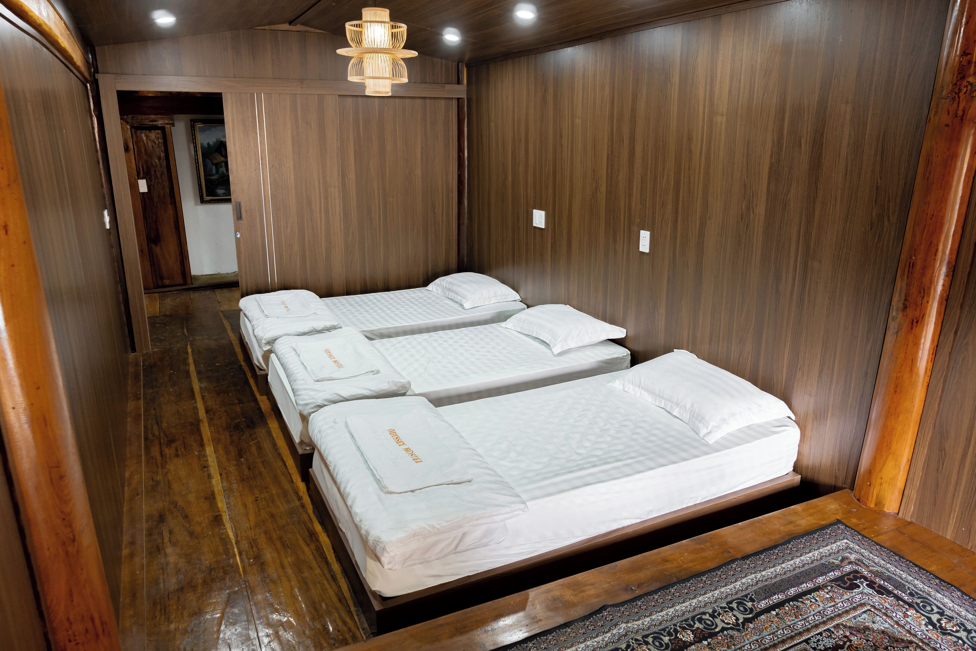 Een kamer met drie eenpersoonsbedden, houten wanden en een houten vloer.