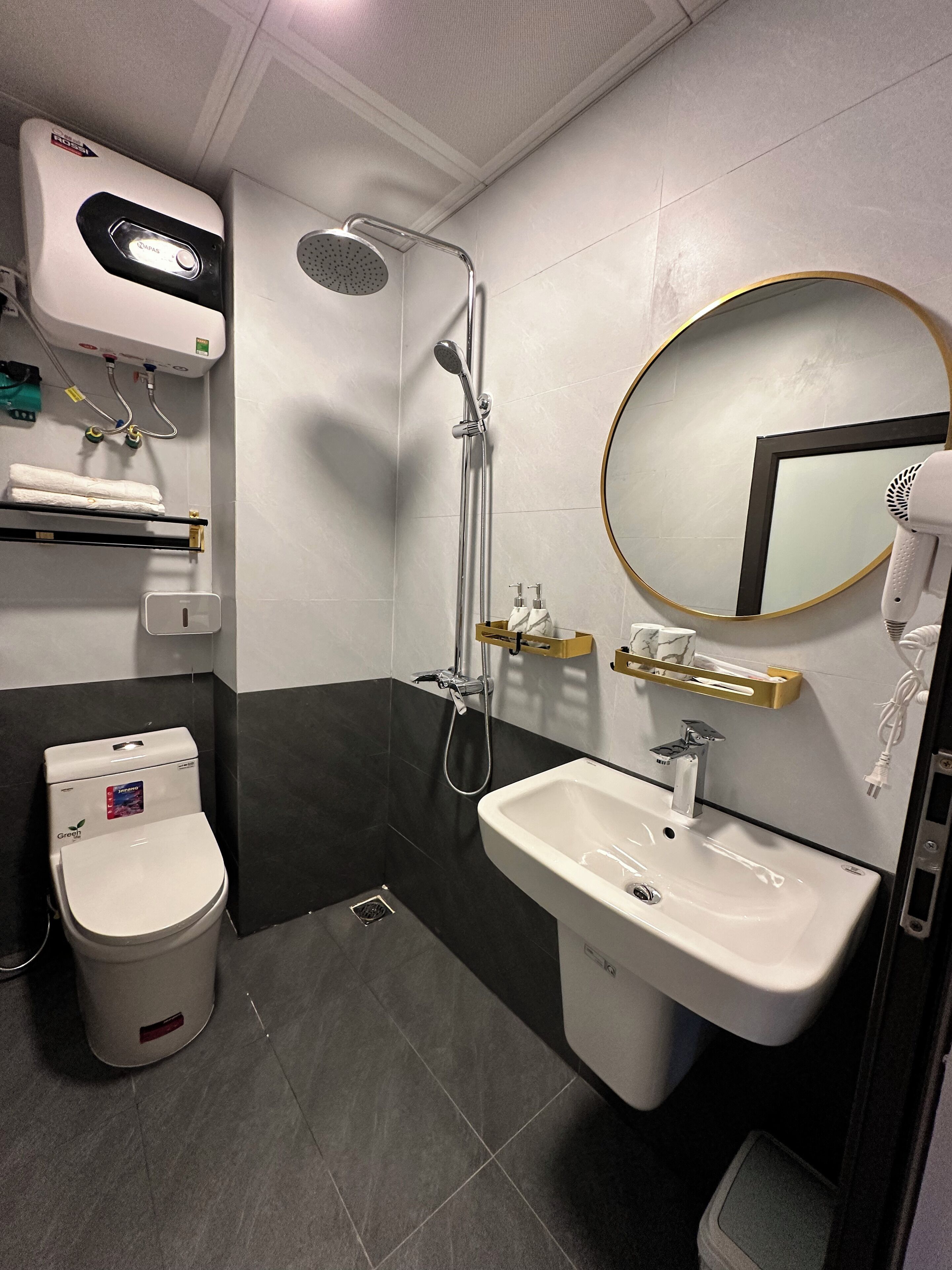 Een moderne badkamer met douche, toilet, wastafel en een spiegel met gouden lijst.