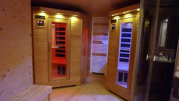 A sauna room with wooden walls, a bench, and glass doors.