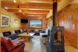 A cozy wooden interior with a sofa, a table, and a fireplace.