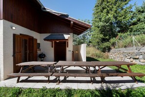 Un bâtiment en bois doté d’un patio couvert, d’un barbecue et d’un mur en pierre.