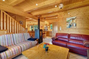 Et interiør i træ med en stribet sofa, en læder sofa i rød farve og et træ sofabord med en plante.