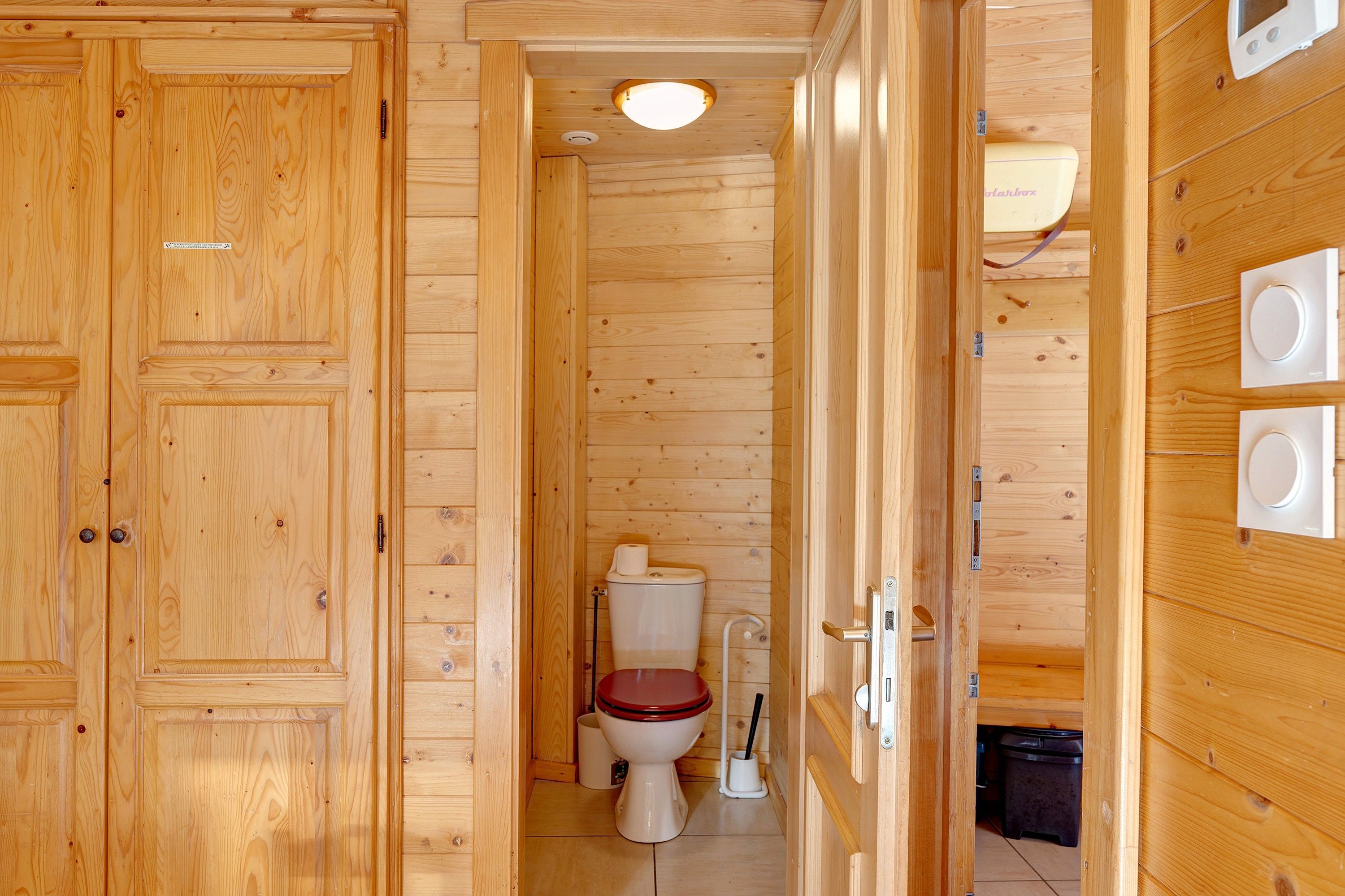 A wooden interior with a toilet, a sink, and a cabinet.
