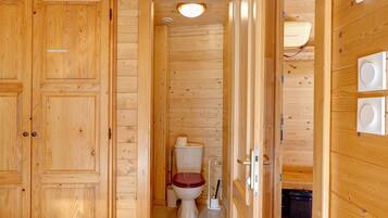 A wooden interior with a toilet, a sink, and a cabinet.