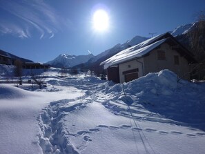 Un paysage enneigé avec un bâtiment, des montagnes et un ciel dégagé.