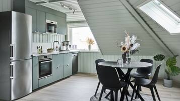 Une cuisine moderne dotée d’une lucarne, d’un coin repas avec des chaises noires et d’une plante en pot.