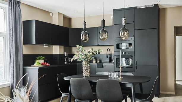 Una cocina moderna con armarios negros, una isla central e iluminación colgante.