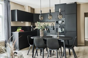 A modern kitchen with black cabinets, a central island, and pendant lighting. - Staysville - Kong Carls Gate (Stavanger)