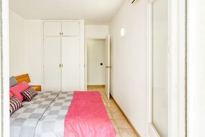 A bedroom with a bed, a wardrobe, and a door leading to another room.
