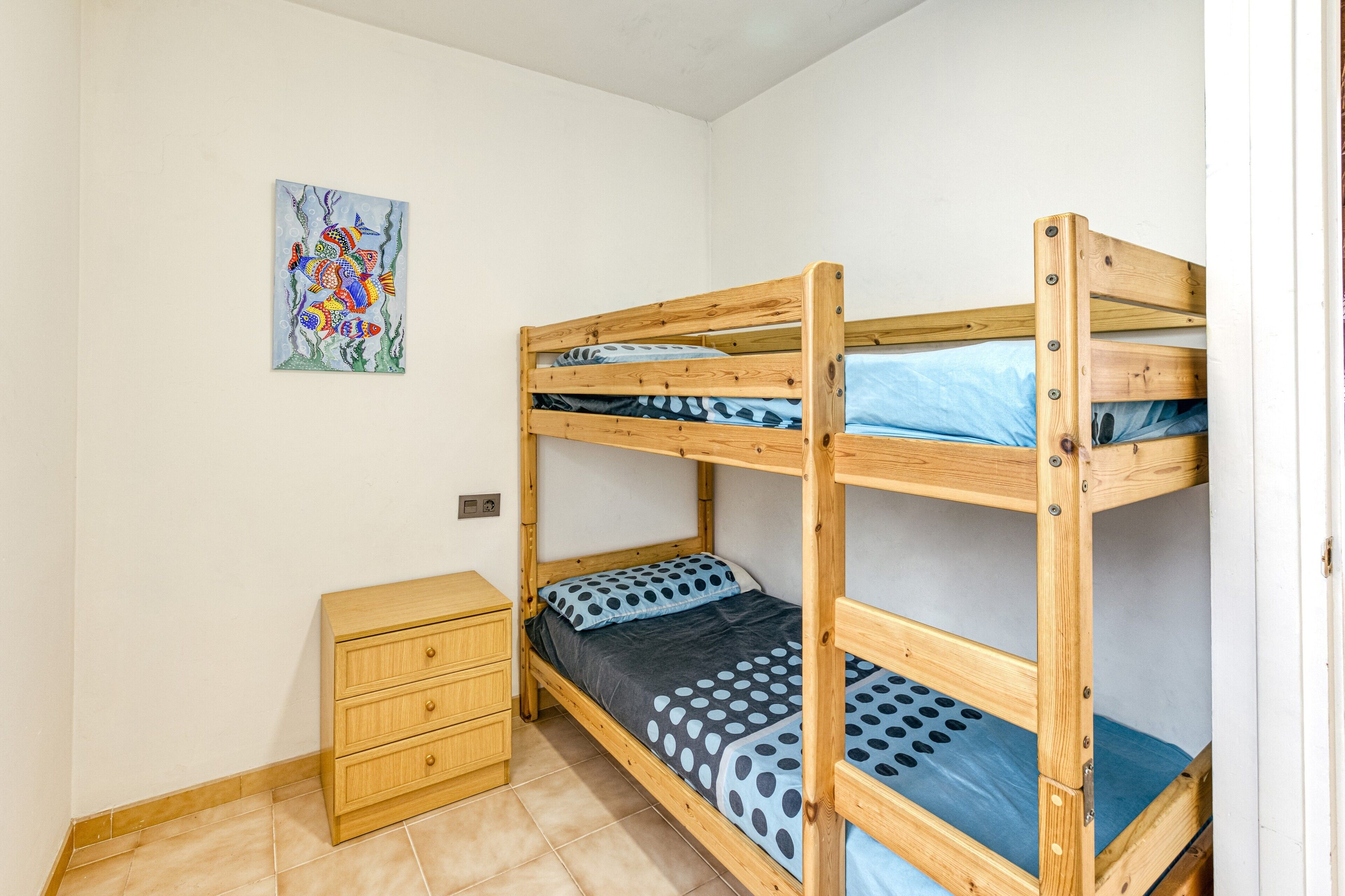 A bunk bed room with a wooden dresser and a painting on the wall.