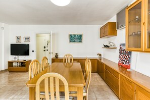 A dining area with a wooden table and chairs, a television, and a cabinet with glass doors.