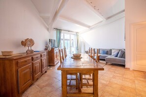 Un coin repas comprenant une table en bois, des chaises, un buffet en bois et un canapé.