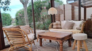 Un rincón al aire libre acogedor con mobiliario de mimbre, una mesa de centro de madera y una alfombra estampada.