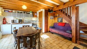 Un interior de madera con una mesa de comedor, sillas, una zona de cocina y una escalera.
