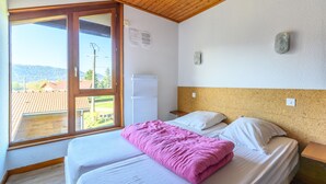 Un dormitorio con cama, ventana, techo de madera y vistas al exterior.