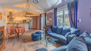 A modern living room with a glass coffee table, a sofa, and a dining area with a table and chairs.