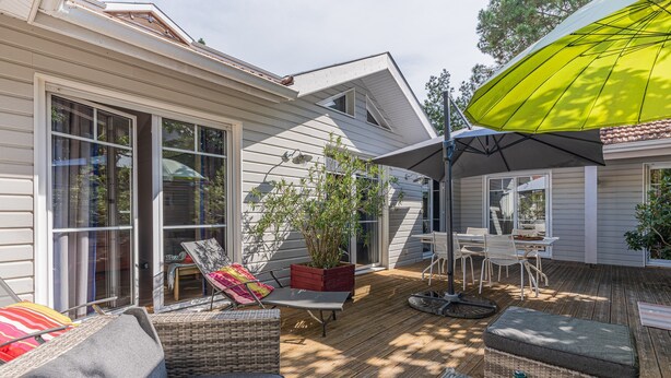 A covered patio with outdoor furniture, a dining area, and a large umbrella.