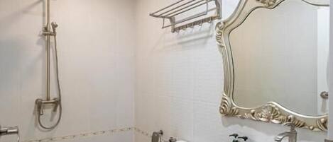 A bathroom with a toilet, a sink, a shower, and a large mirror.