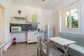 Une cuisine compacte équipée d’un four à micro-ondes, d’un évier et d’un réfrigérateur. On y trouve également un extincteur, une petite table et un banc.
