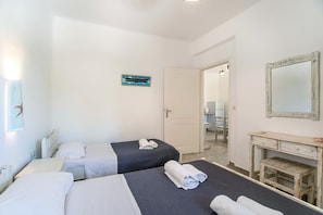 Une chambre d’hôtel avec deux lits, un bureau, un miroir et une porte donnant sur une salle de bain.