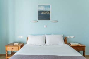 Een slaapkamer met een bed, twee nachtkastjes, een wandlamp en een lichtschakelaar.