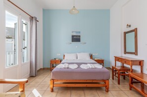 Een slaapkamer met een bed, nachtkastjes, een bureau, een spiegel en een schilderij aan de muur.