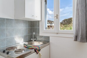 Een koelkast, een kookplaat, een waterkoker, kookgerei, borden en bestek