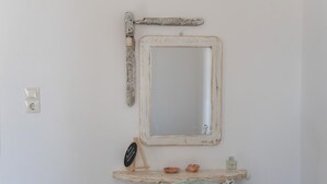 A bathroom with a rustic mirror, a small shelf with a soap dish, and a wall-mounted light switch. - Holiday Home 'Green Retreats 5 Paros' with Mountain View, Wi-Fi and Air Conditioning (Glifades)
