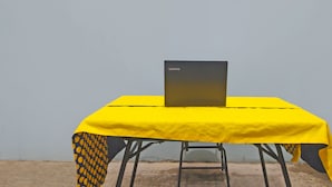 A table with a laptop on it, covered by a yellow tablecloth with a black and yellow pattern. - Hotel O Pondok Karisma Syariah (Tasikmalaya)