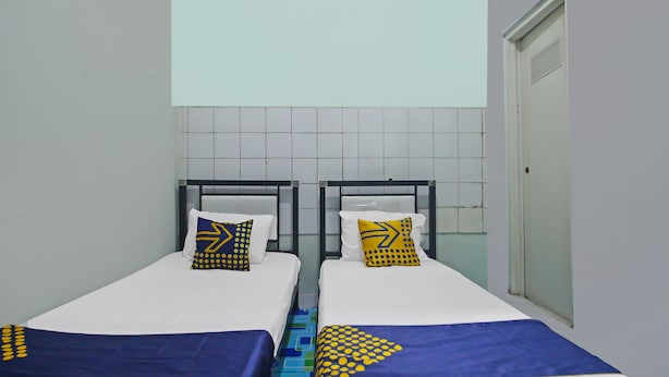 A twin room with two beds, each with a blue and white bedspread, and matching pillows with yellow and blue patterns. - Hotel O Pondok Karisma Syariah (Tasikmalaya)