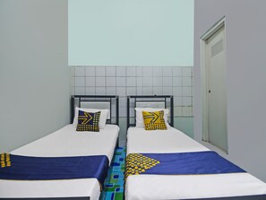 Ein Doppelzimmer mit zwei Betten, jeweils mit blauer und weißer Bettdecke sowie passenden Kissen mit gelb-blauen Mustern.